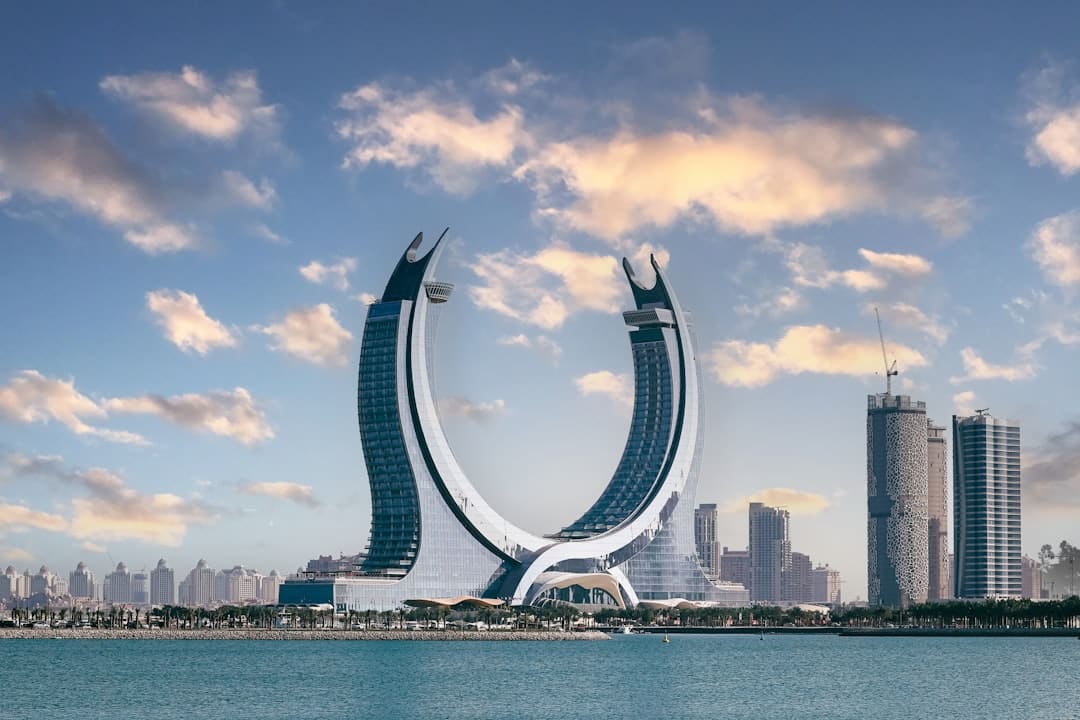 Crescent Tower and the Doha, Qatar skyline reflected on the water at dusk.